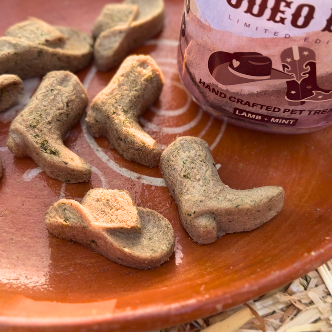 Dog treats shaped like cowboy boots on a plate with a bottle of Rodeo Limited Edition pet treats in the background.